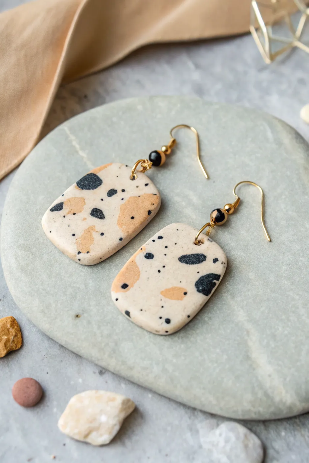 Granite-inspired clay earrings in clean shapes, styled on stone for a calm minimalist mood.
