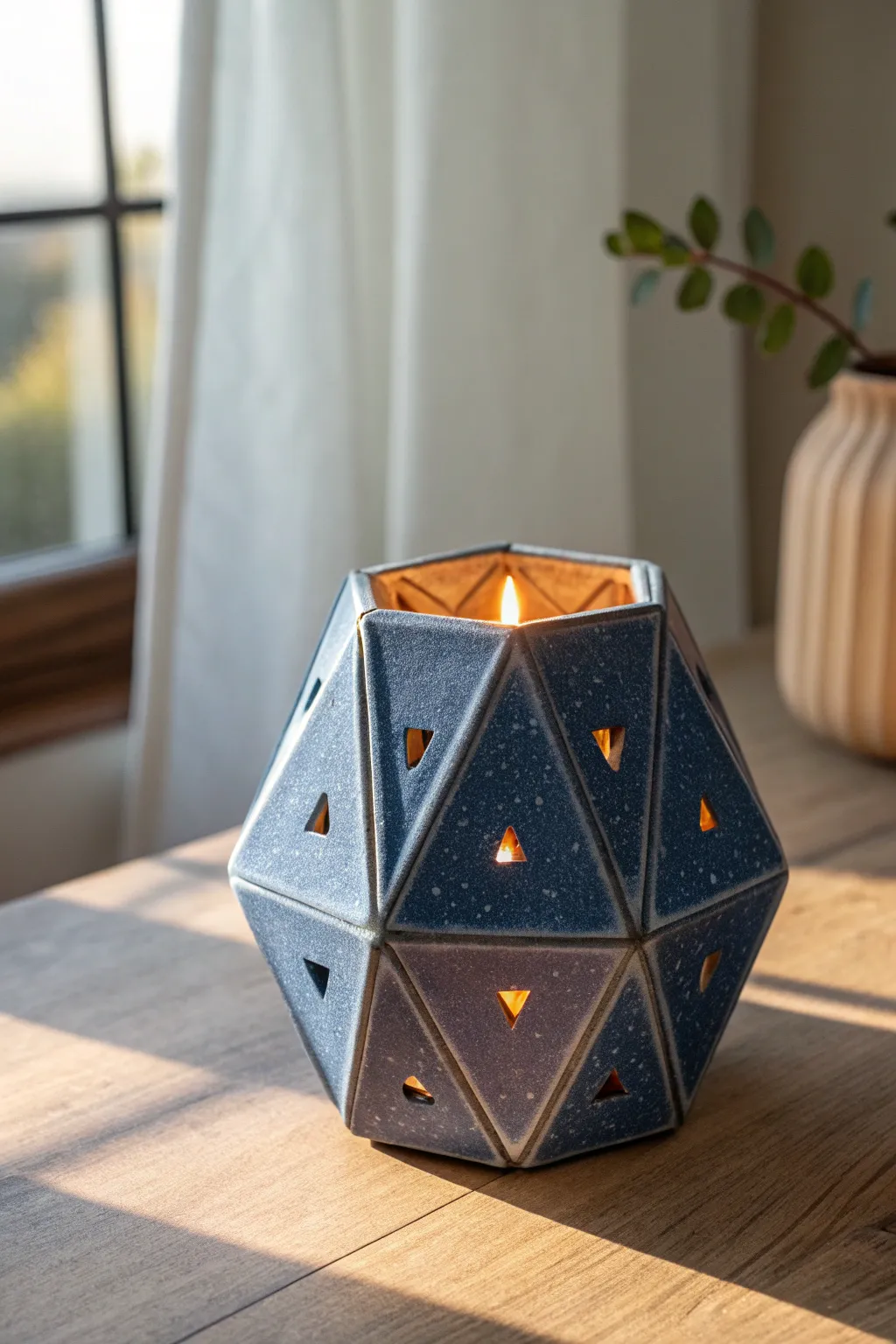 Modern faceted clay lantern with triangle cutouts, casting crisp geometric shadows in warm light.