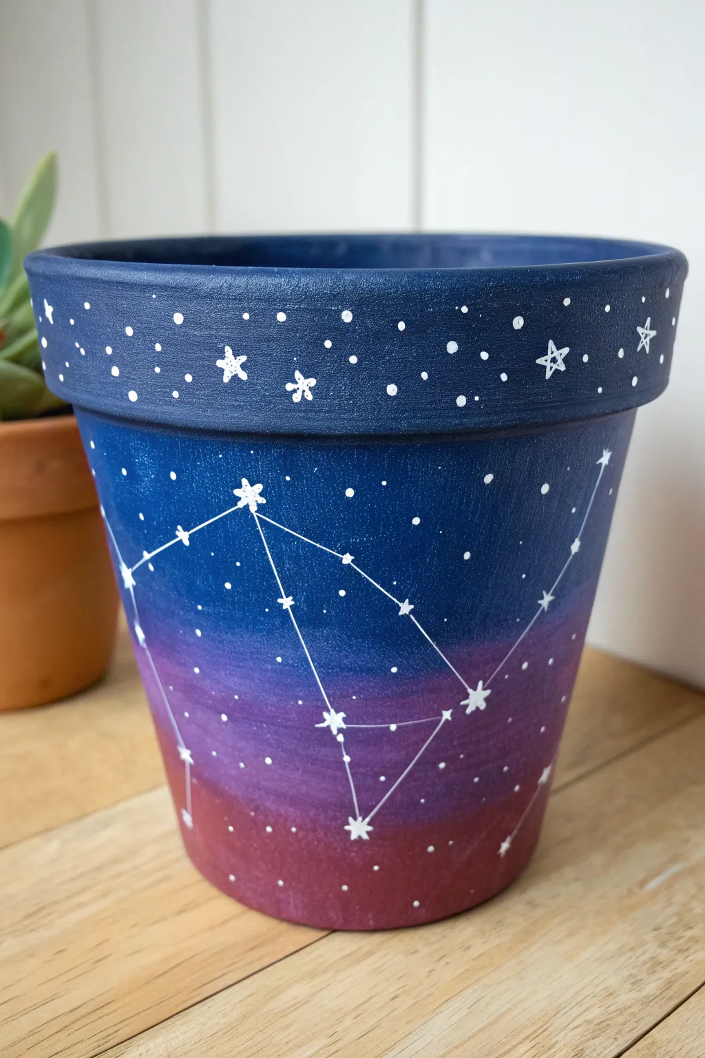 Night-sky galaxy terracotta pot with splatter stars, bold color pop on a calm neutral backdrop.