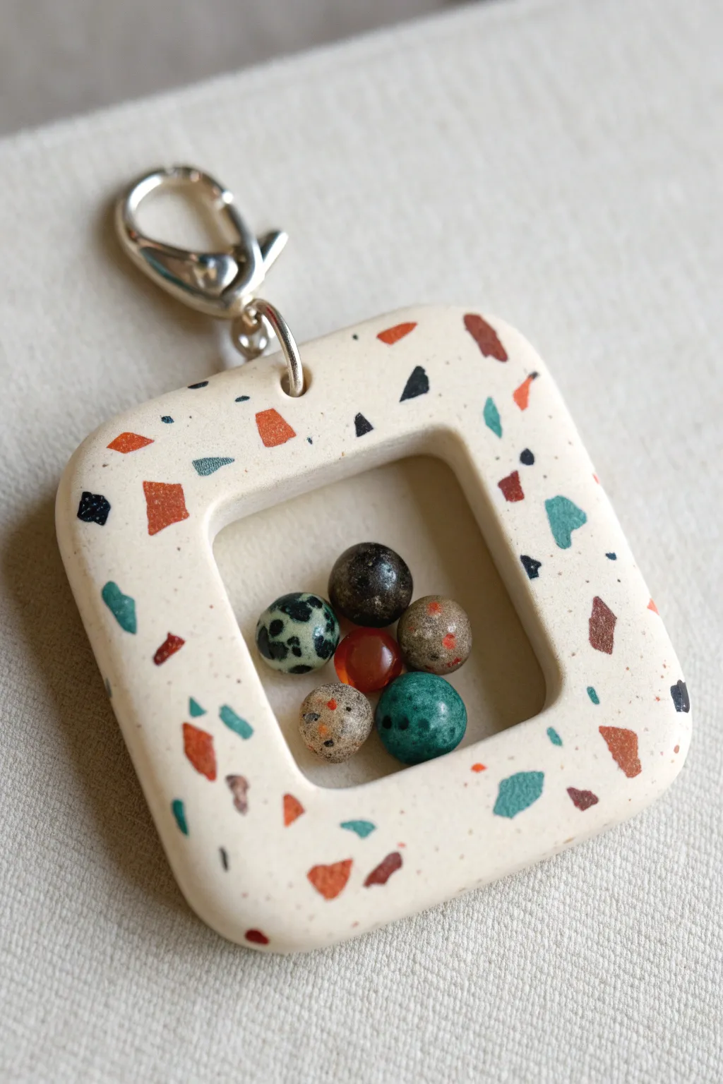 Terrazzo-speckled clay shaker charm with a clear window and beads for a bold minimalist look.