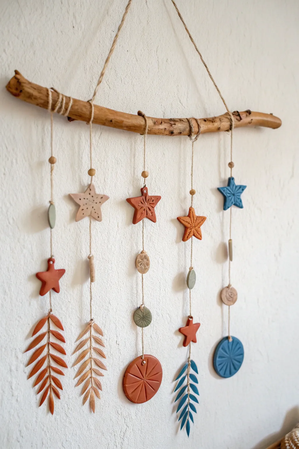 Driftwood branch wall hanging with simple clay charms in bold boho colors and calm minimal style