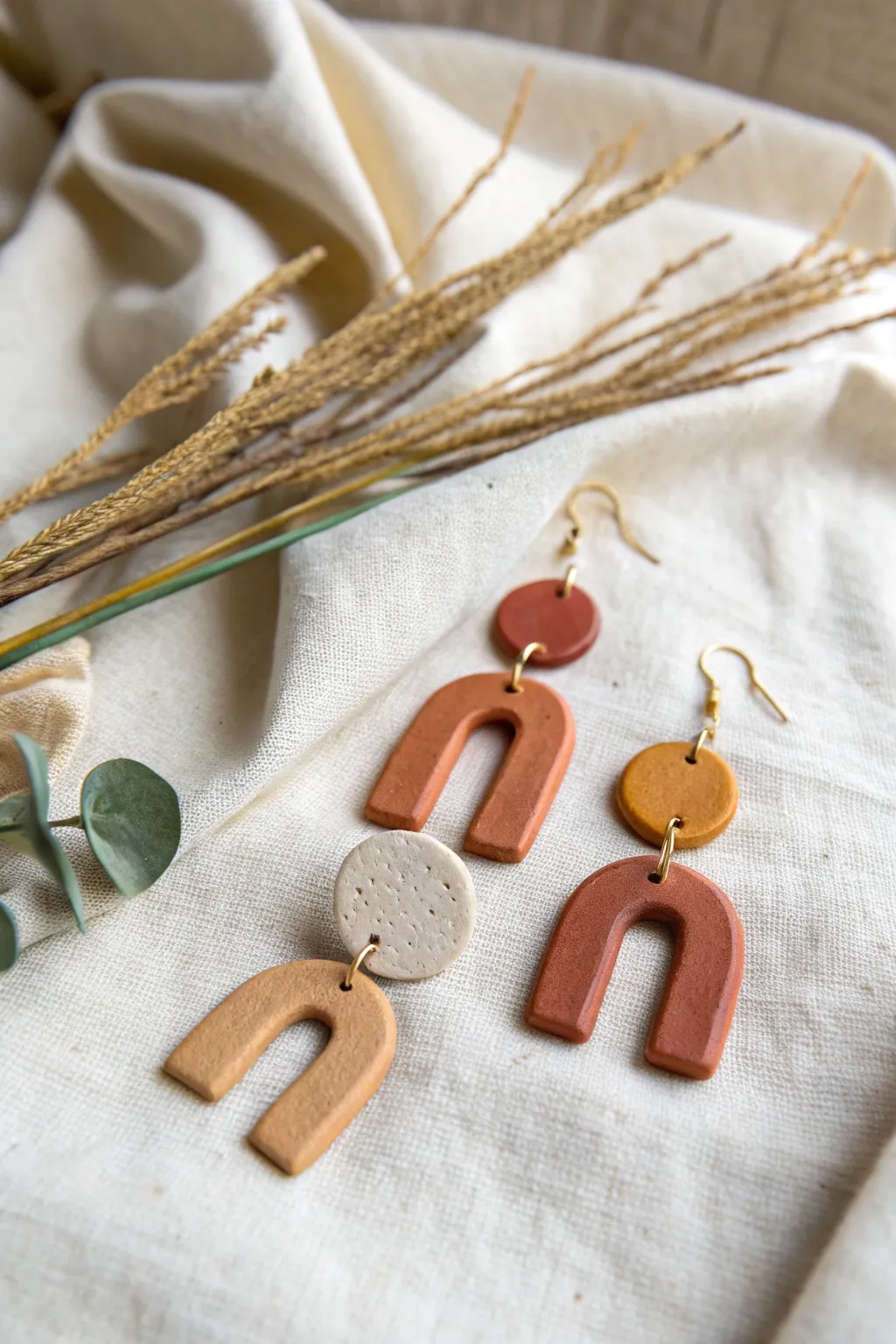 DIY air dry clay statement earrings in bold arches, styled on linen for a chic minimal boho look.