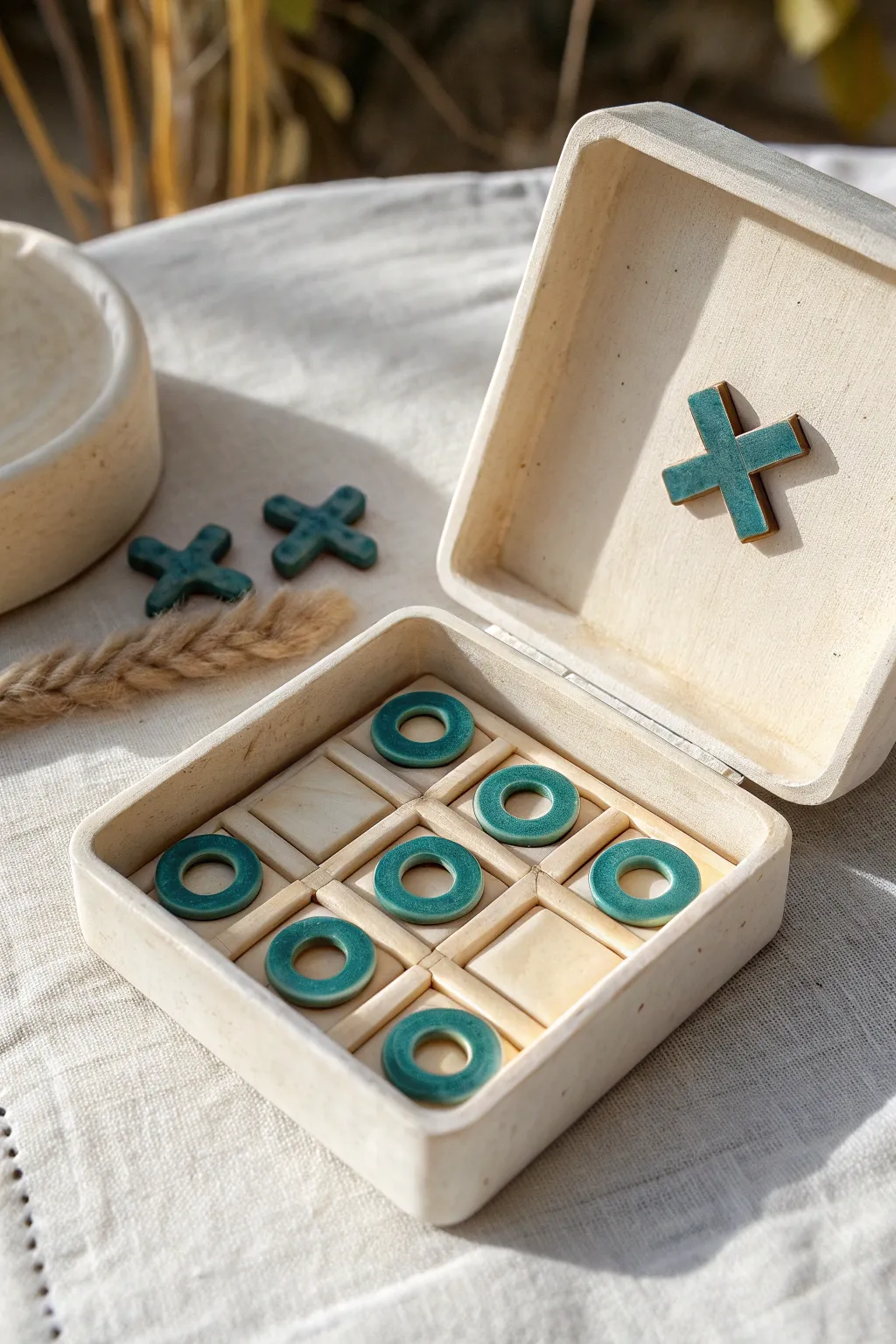 A lidded clay tic tac toe trinket box that stores its own pieces for a cute keepsake game.