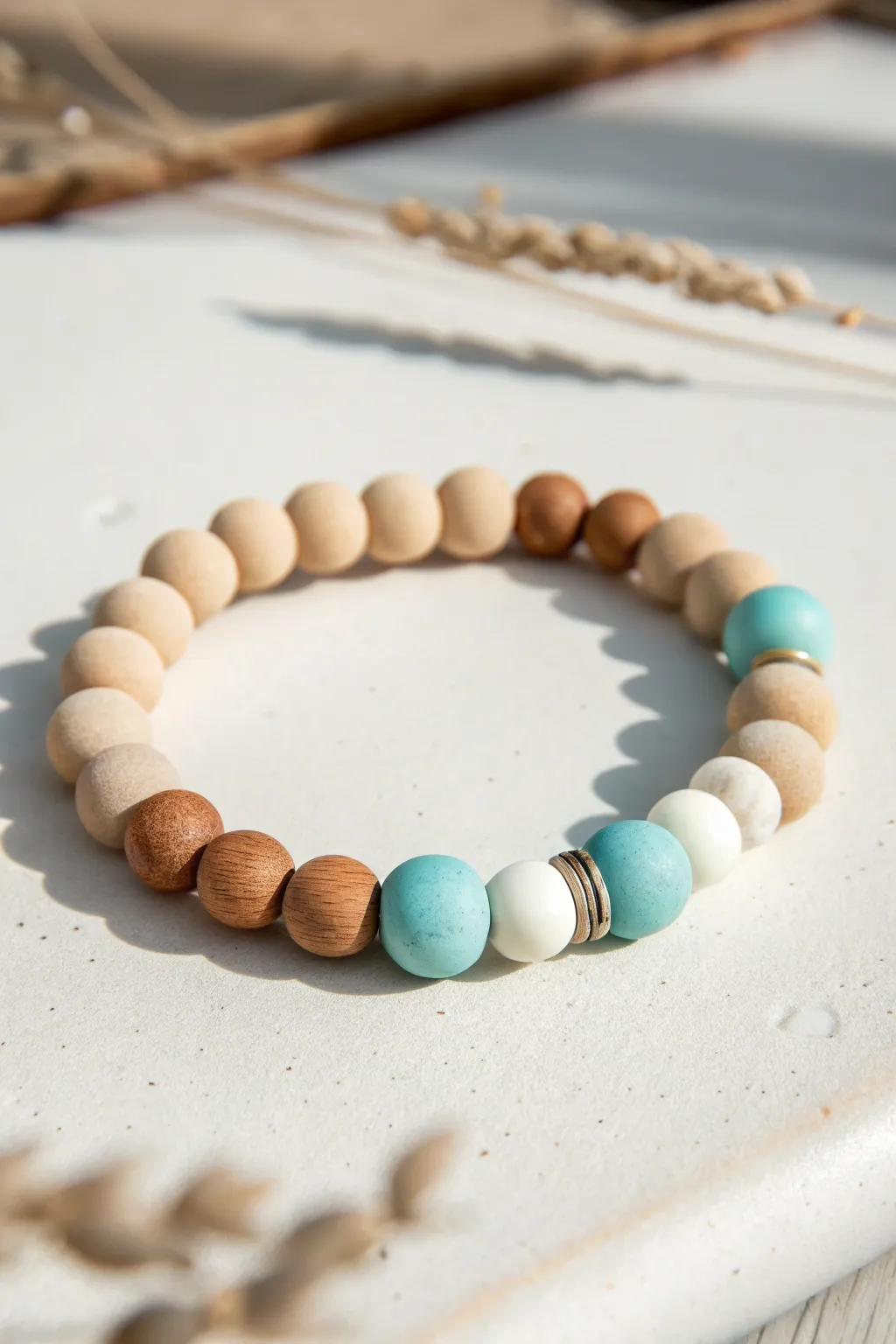 Beachy clay bead bracelet in sandy neutrals and ocean blues, minimalist coastal charm.