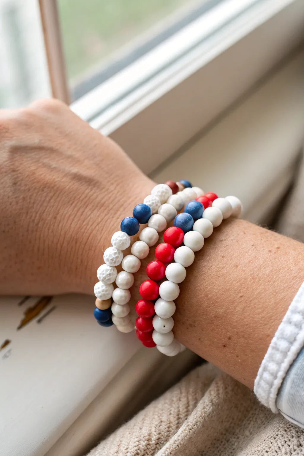 Fourth of July bracelet inspo: clean white clay beads with bold red and blue pops, stacked chic.