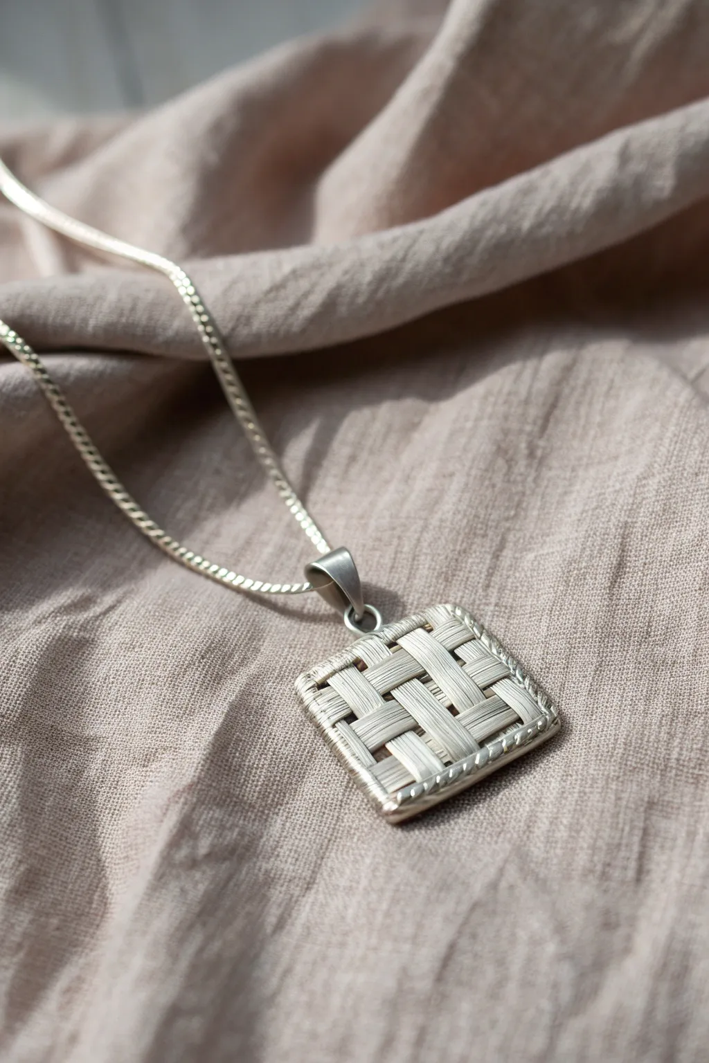Woven metal clay paper pendant with a clean Nordic look, side-lit to highlight texture.