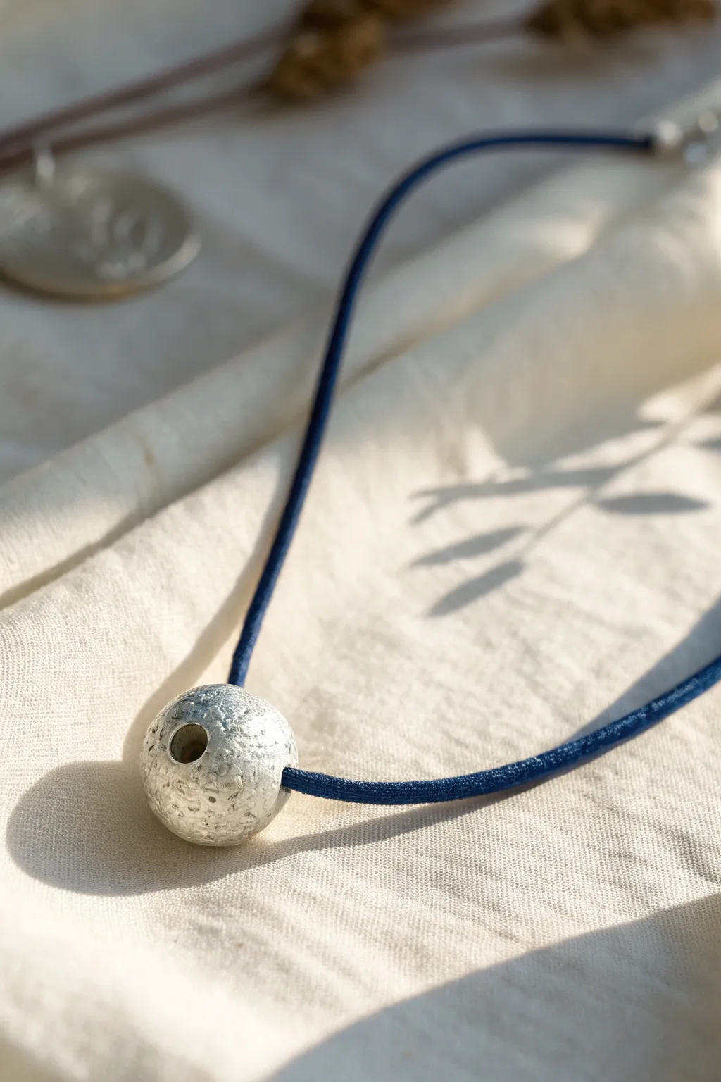 Hollow silver clay bead focal necklace with subtle texture, styled on linen for modern boho calm.