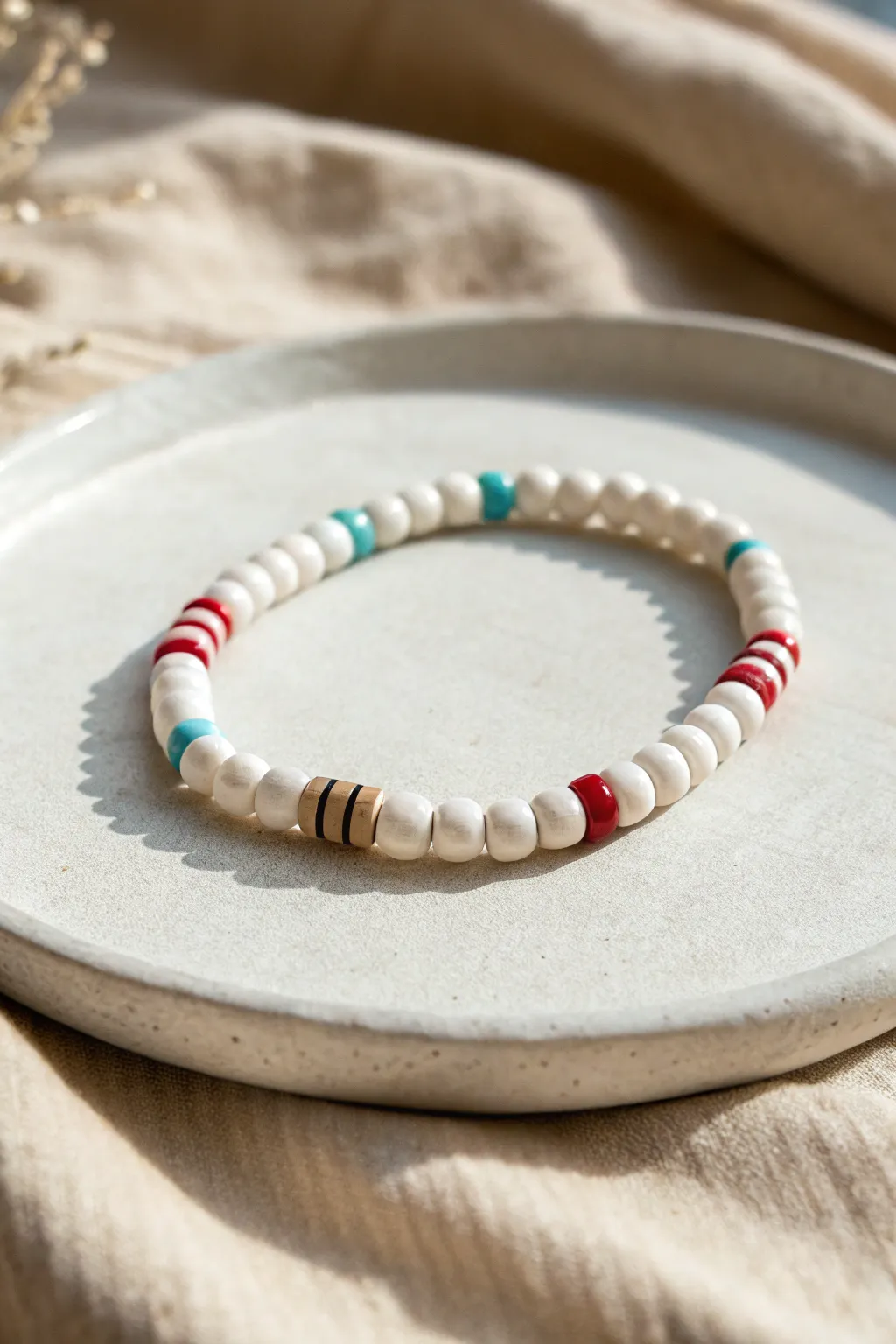 Minimal school-style clay bead bracelet with white, pale blue, and a thin red stripe.