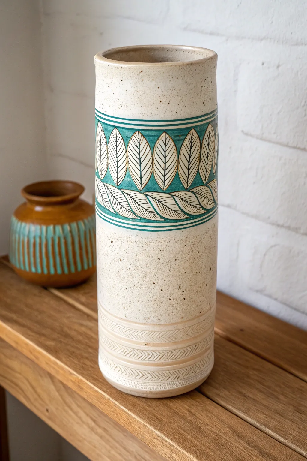 Minimal slab cylinder vase with carved sgraffito band in bold earthy hues and soft studio light