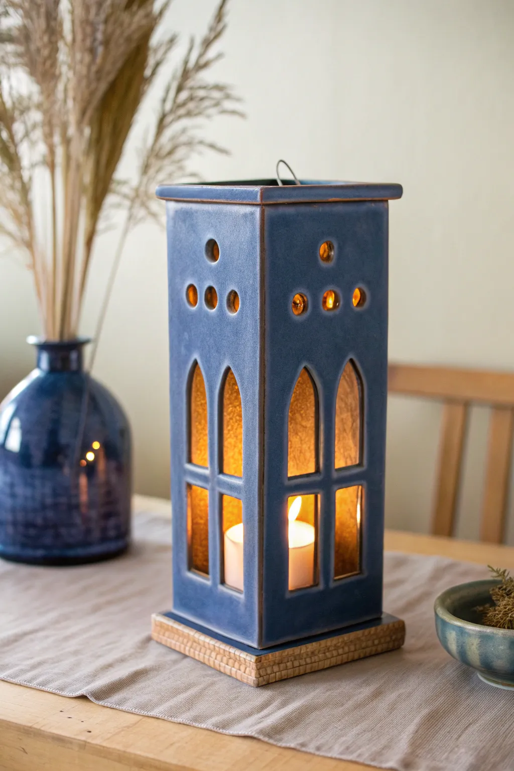 Minimal slab lantern vessel with simple cutout windows, warm glow, bold glaze, cozy contrast.