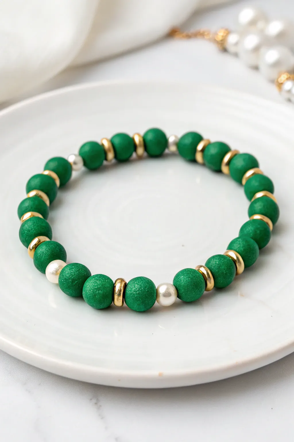 Lucky luxe bracelet idea: emerald heishi clay beads with pearls and gold spacers on crisp white
