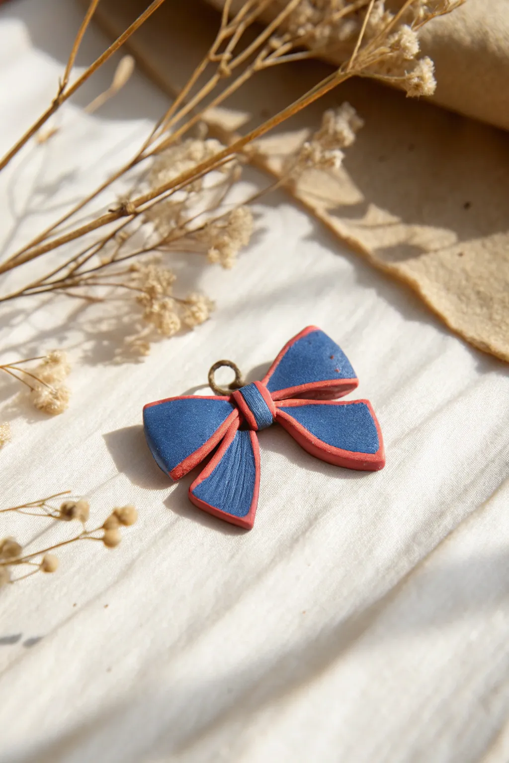 Tiny air-dry clay bow knot charm in a bold color, minimalist and sweet, perfectly sized to hang.
