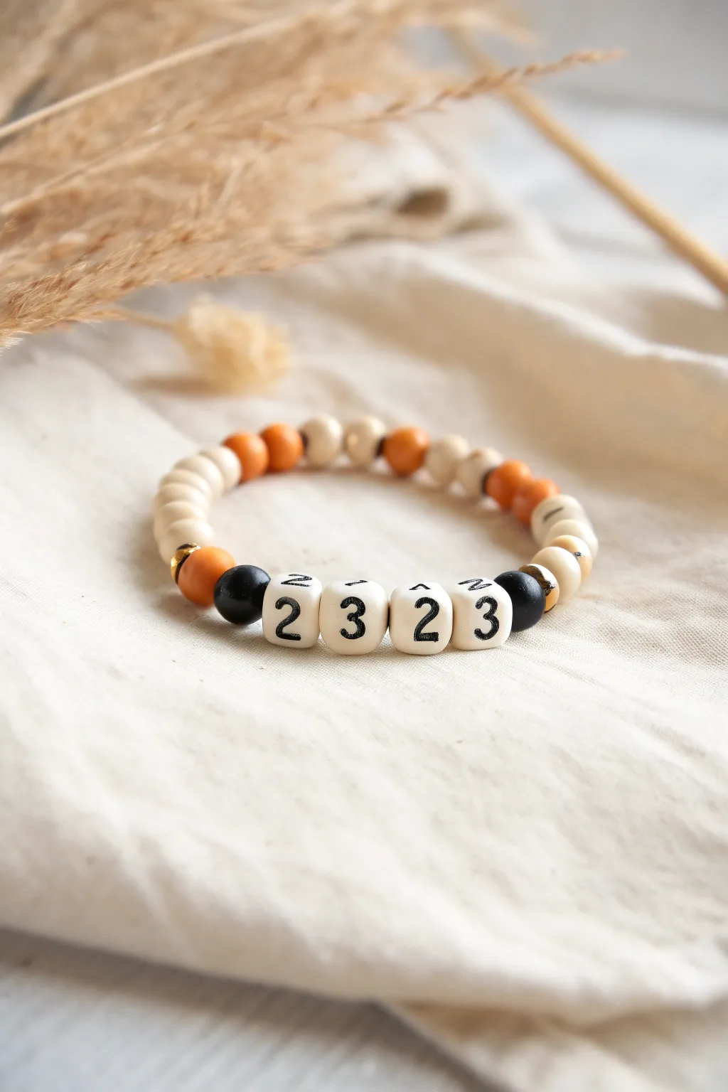 Scoreboard-inspired clay bead bracelet with repeating 2 3 pattern and orange-black heishi beads.