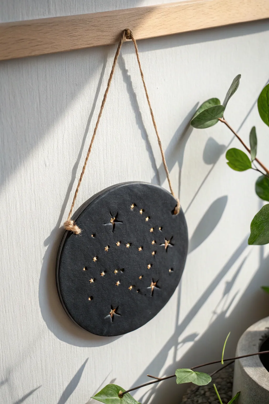 Matte black clay constellation plaque, simple starry glow on an airy Scandinavian wall