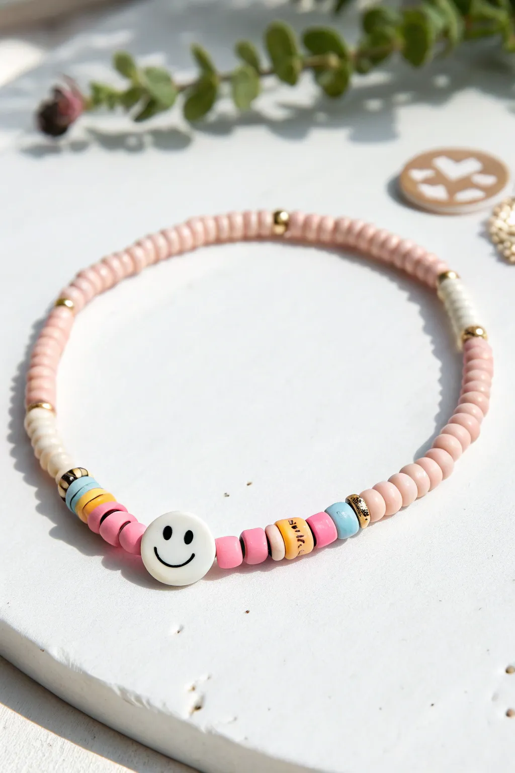 Smiley and heart focal beads brighten simple heishi clay bracelet in minimalist Scandinavian style.