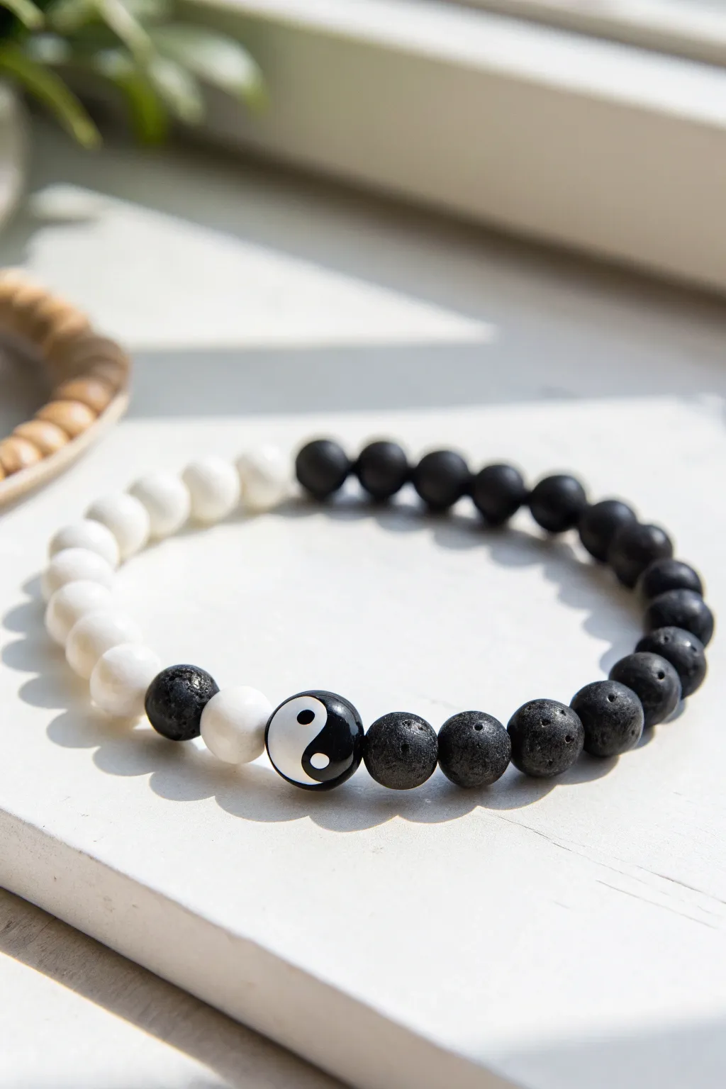 Minimal yin-yang clay bead bracelet in black and white, a serene graphic centerpiece.