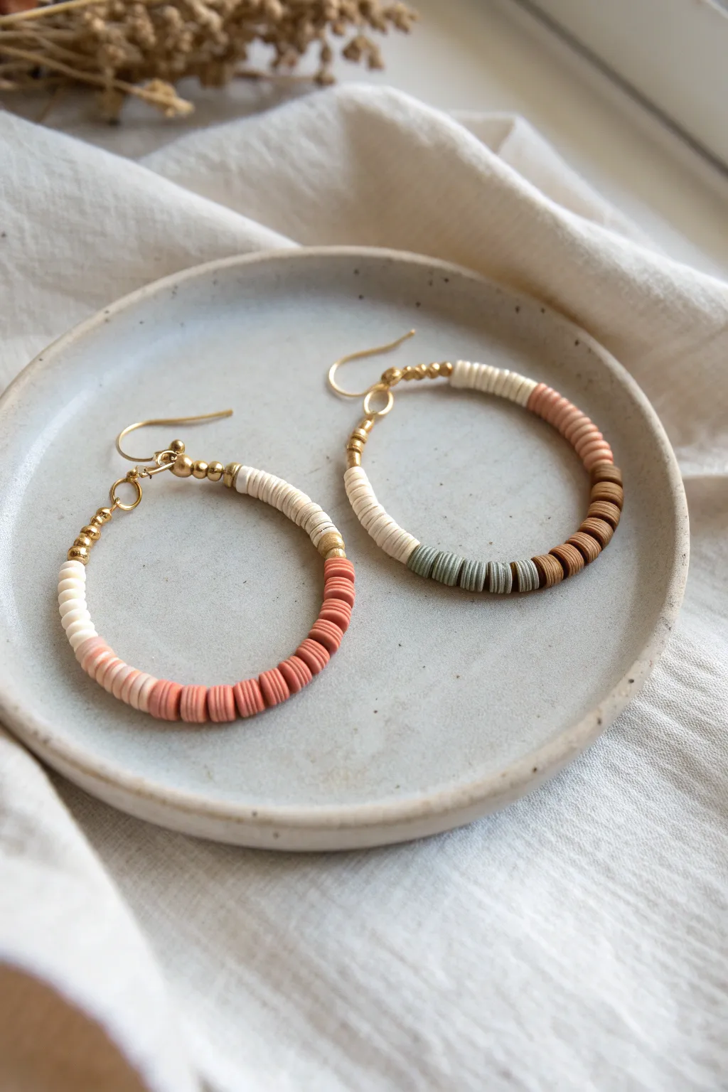 Mismatched clay heishi hoop earrings: one ombre, one color-blocked in a shared earthy palette.