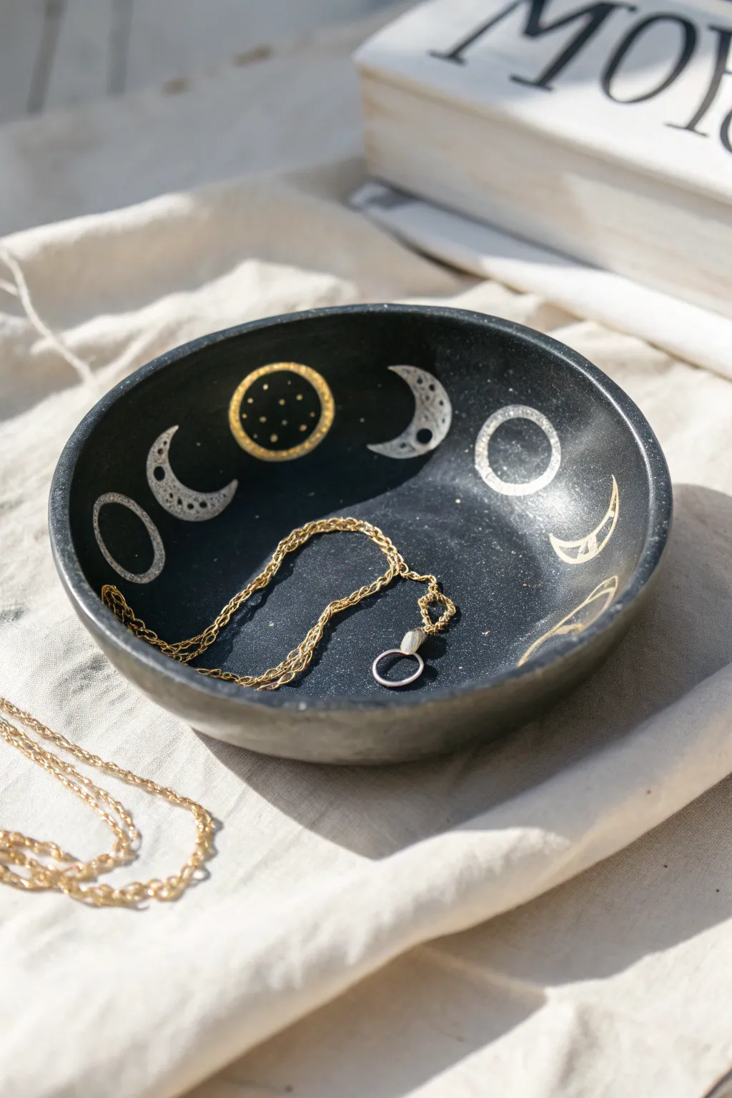 Deep blue moon-phase clay dish with a delicate necklace, minimalist celestial charm.