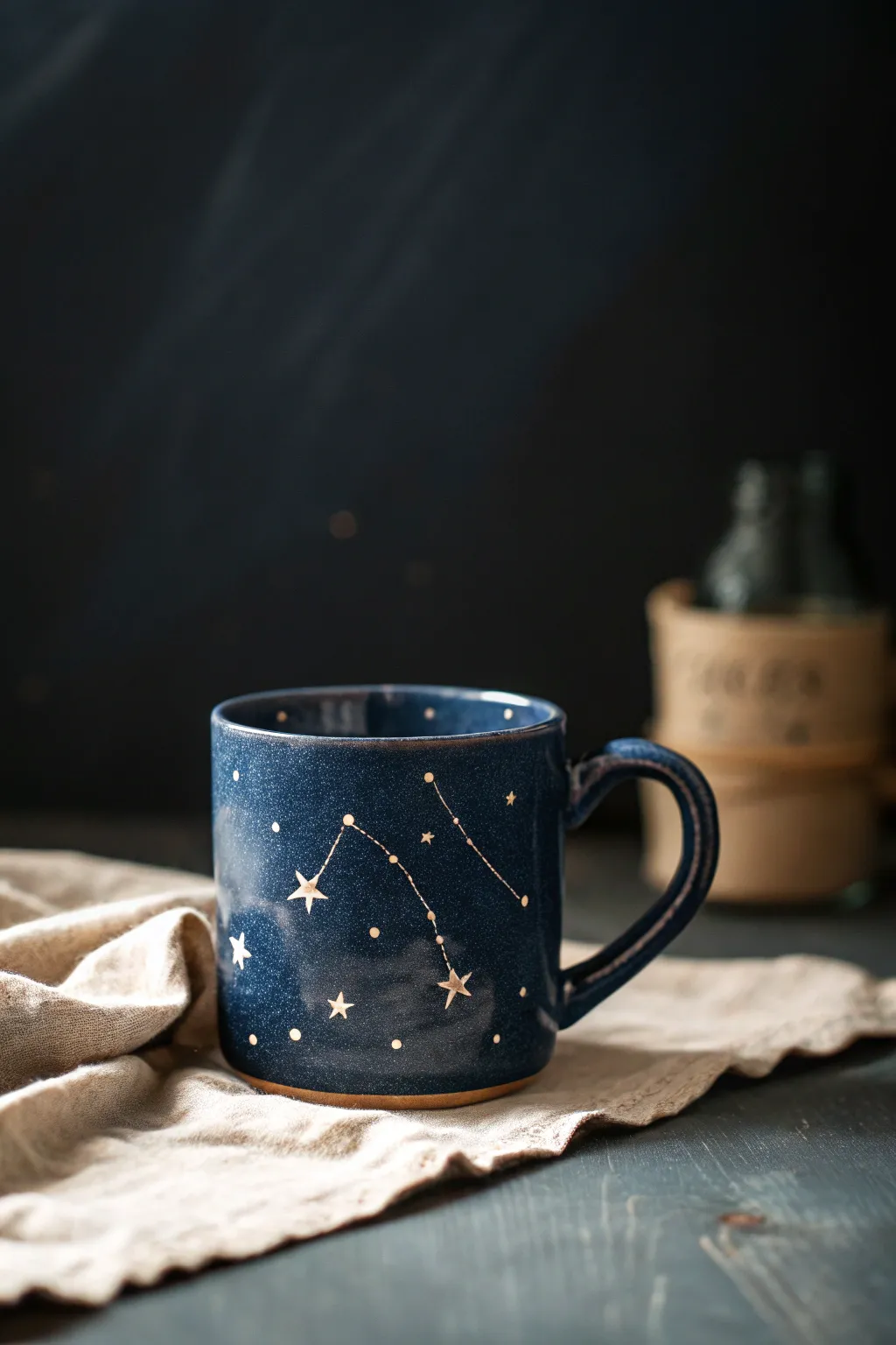 Dark navy clay mug painted with tiny stars and simple constellations, minimalist and dreamy.