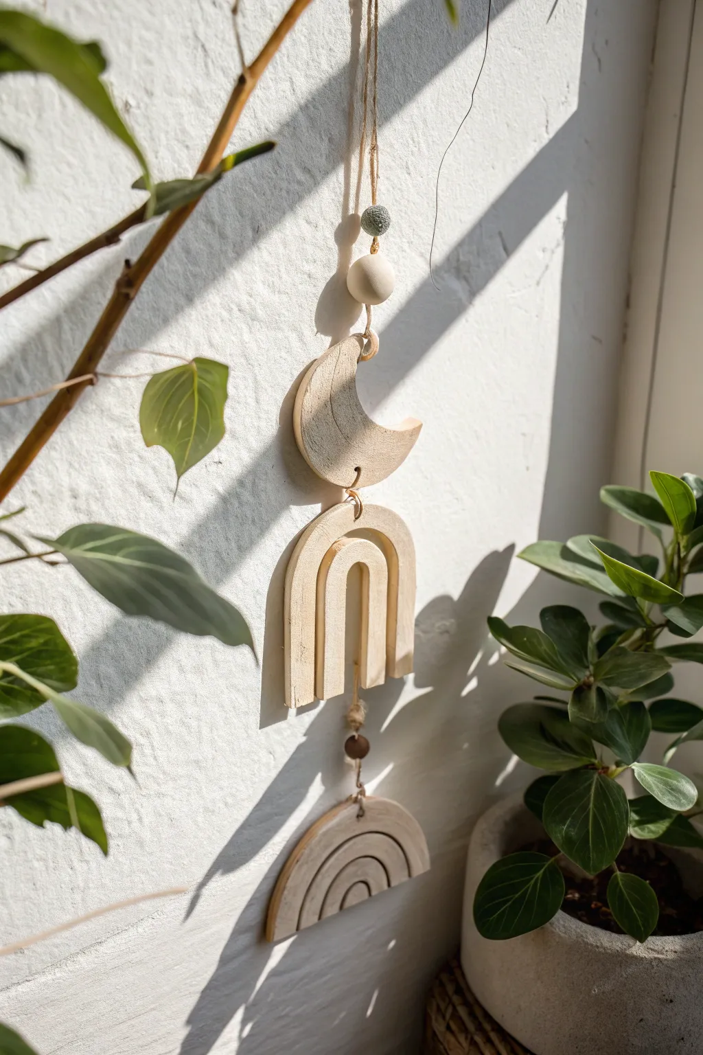 Minimal clay suncatcher with simple cutouts, glowing by a bright window and casting soft shadows
