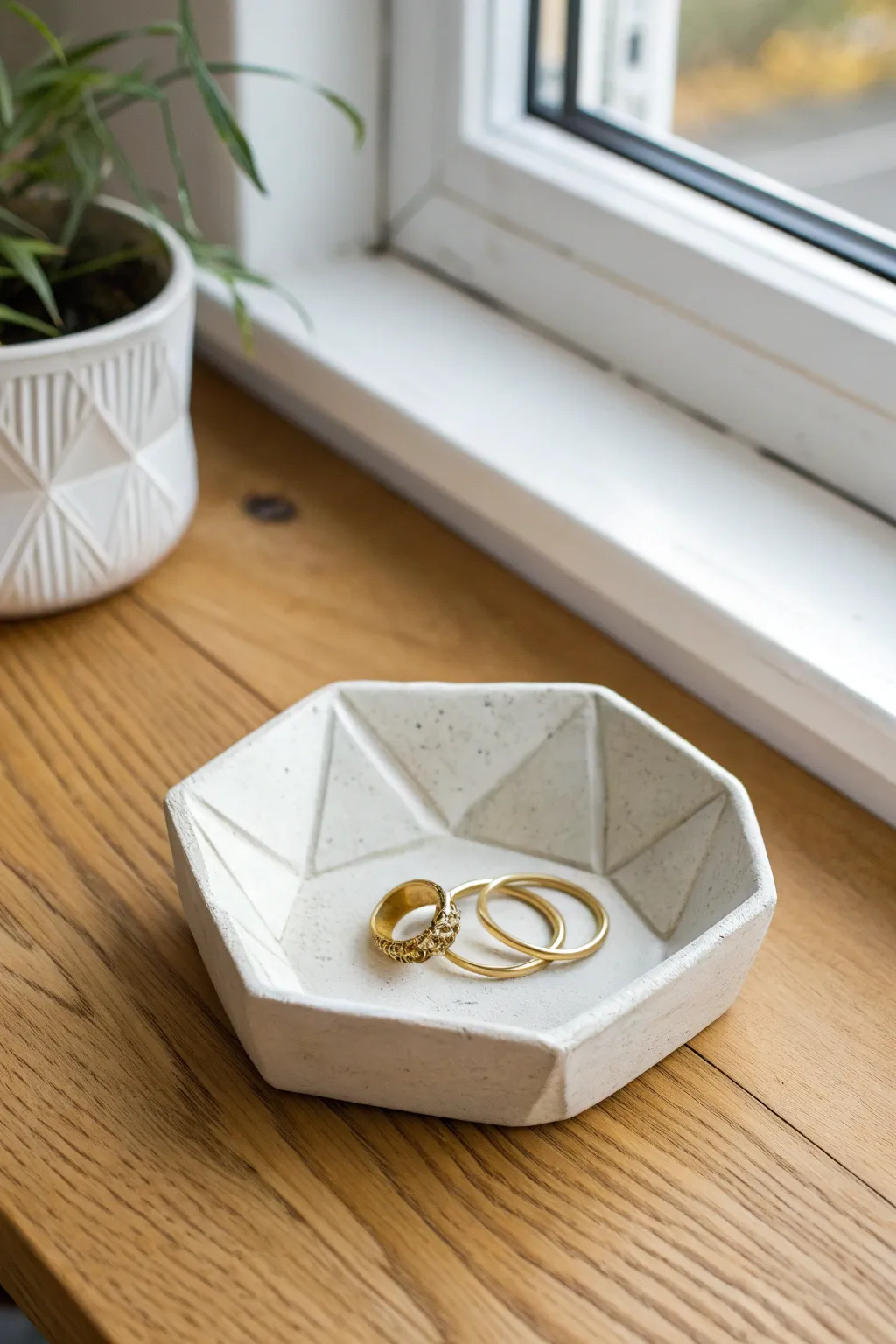 Modern faceted clay trinket tray, softly styled with rings and a hair clip on linen.