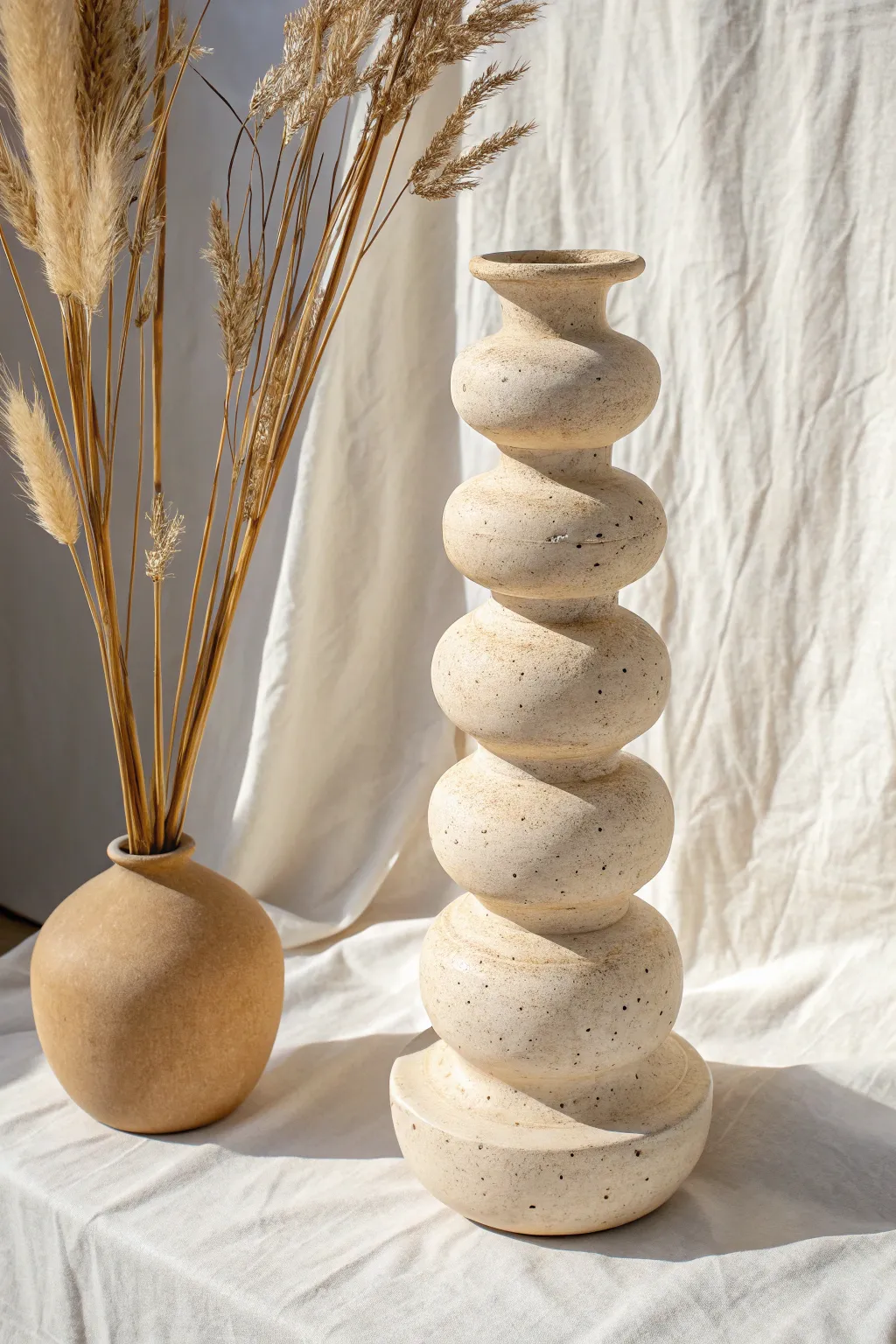 Totem-style ring stacked clay vase in matte neutral tones, finished with airy pampas stems.