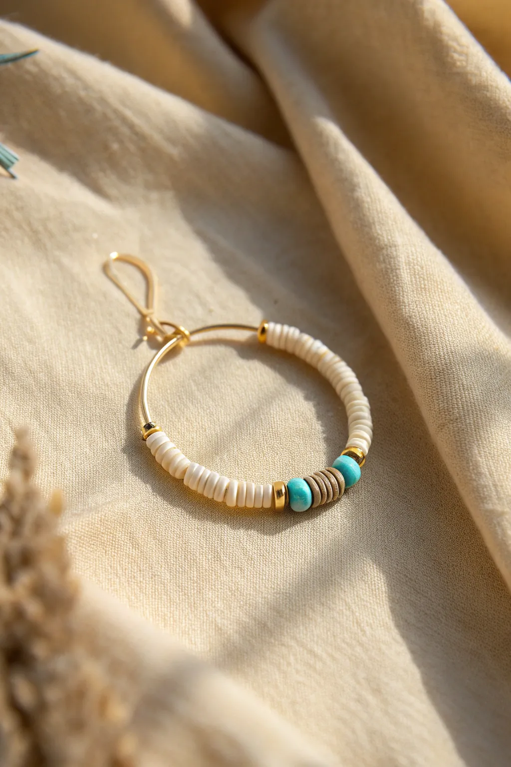 Neutral heishi hoop with one turquoise accent for a simple, modern clay bead statement.
