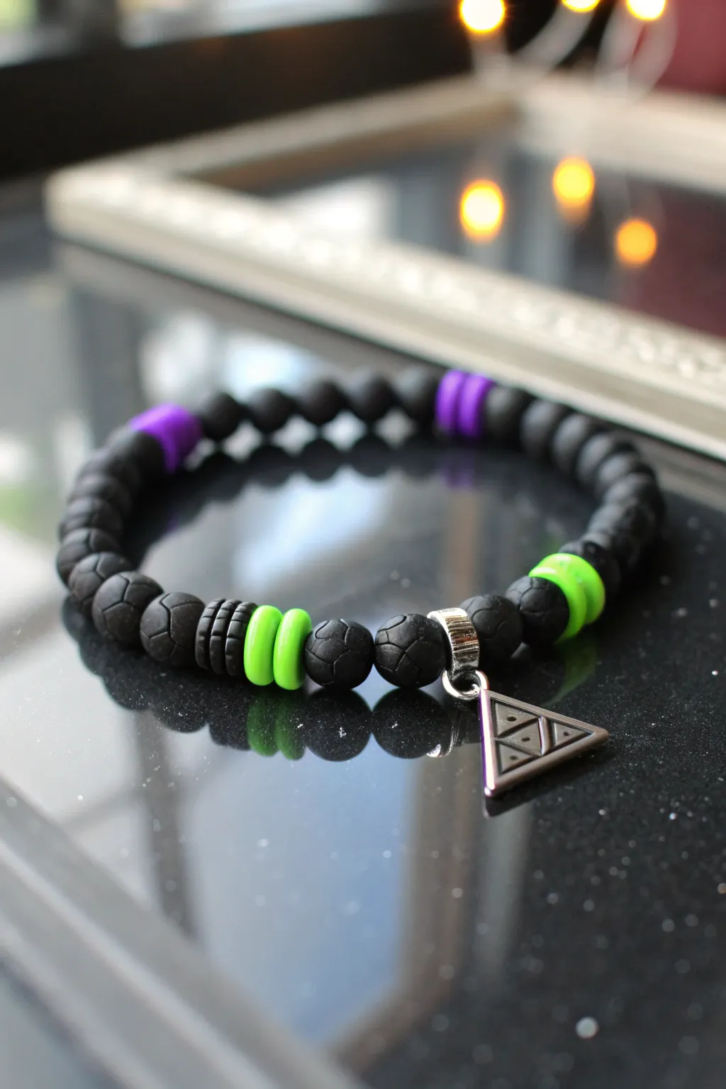 Villain-inspired bracelet: matte black clay disc beads with neon pops and a sharp geometric charm