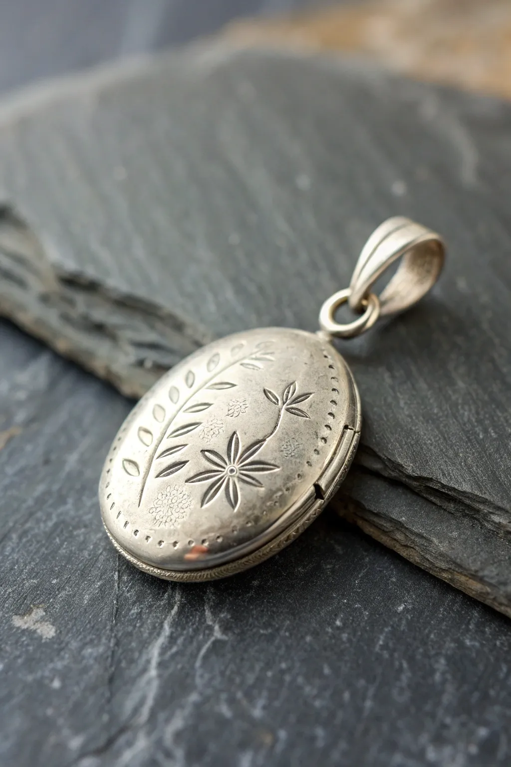 Textured hollow locket pendant in metal clay, minimal and moody close up on dark slate.