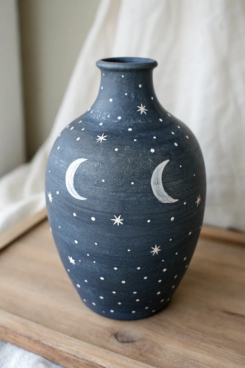Moody night-sky mud vase with simple star dots and crescent moons in calm natural light