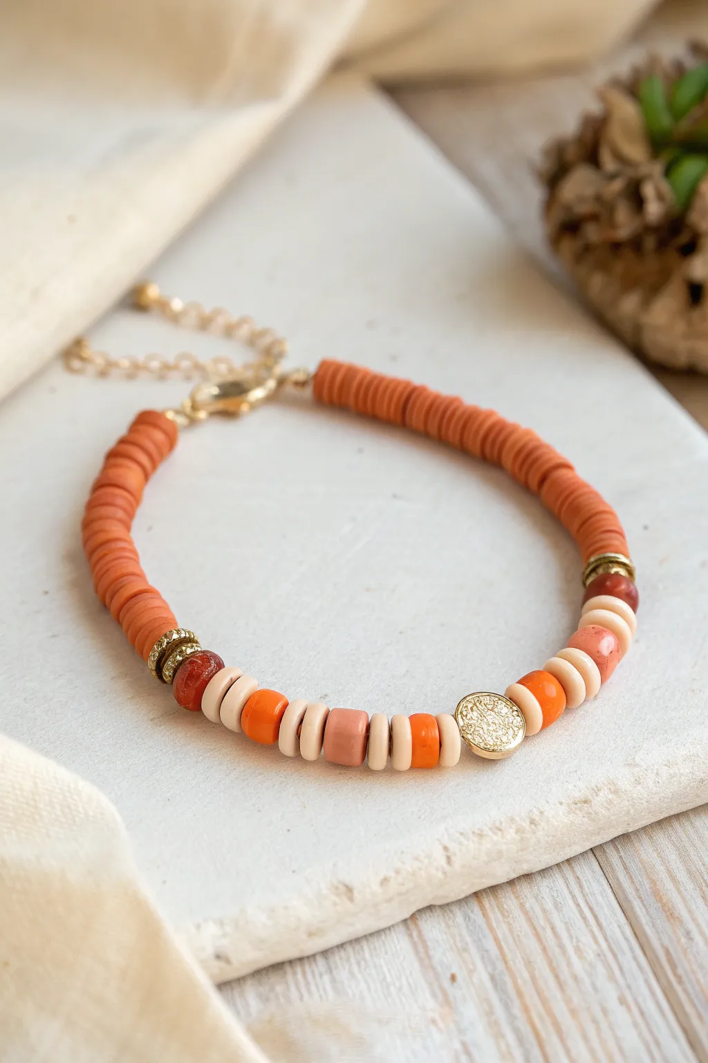 Asymmetrical orange heishi bracelet with an off-center cluster for a modern statement look.