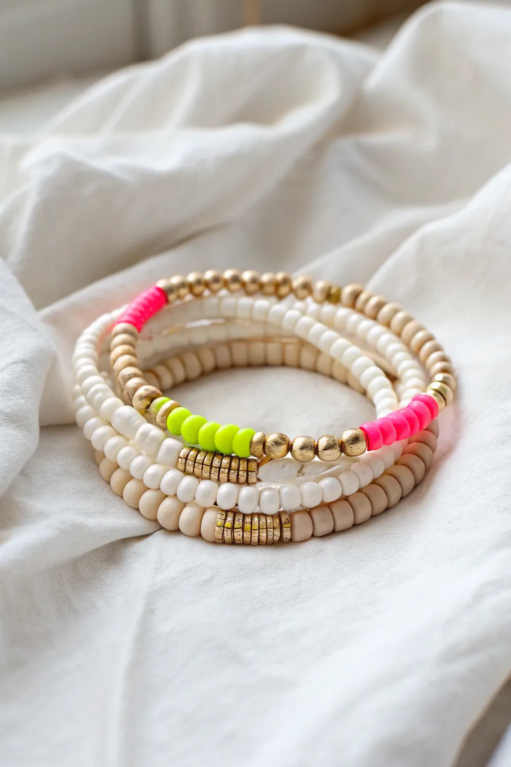 Monochrome heishi stack with one neon pop for a crisp, preppy statement look