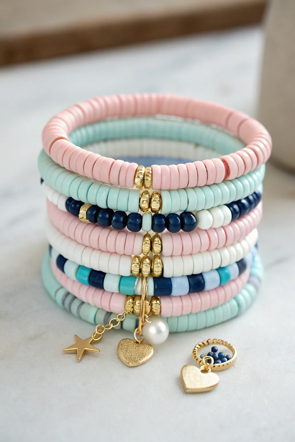 Preppy heishi stack with gold spacers and one bold charm cluster for an easy statement.