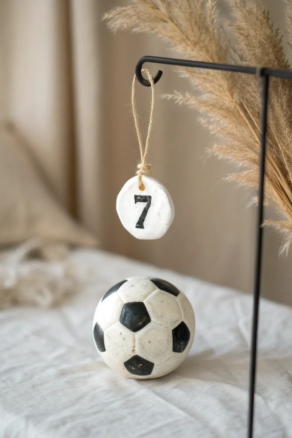 Minimalist clay soccer ball ornament with a tiny numbered tag, styled ready to hang.