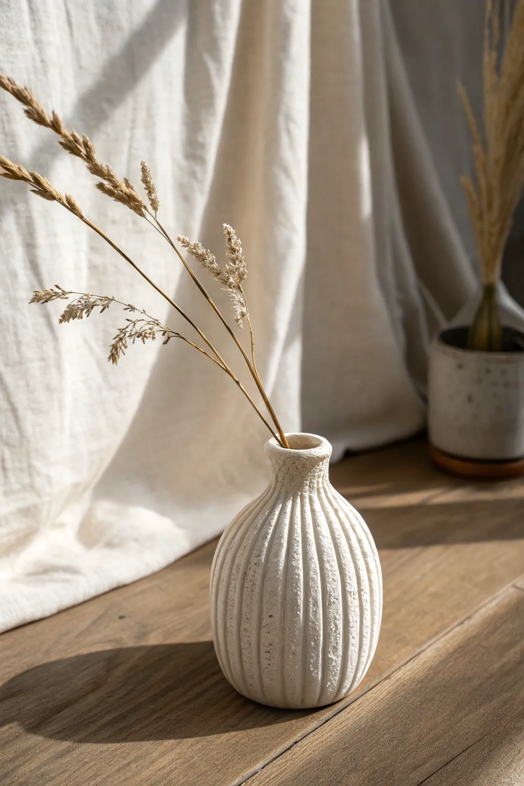 Tiny air dry clay bud vase sleeve with carved texture, styled minimal with one simple stem.