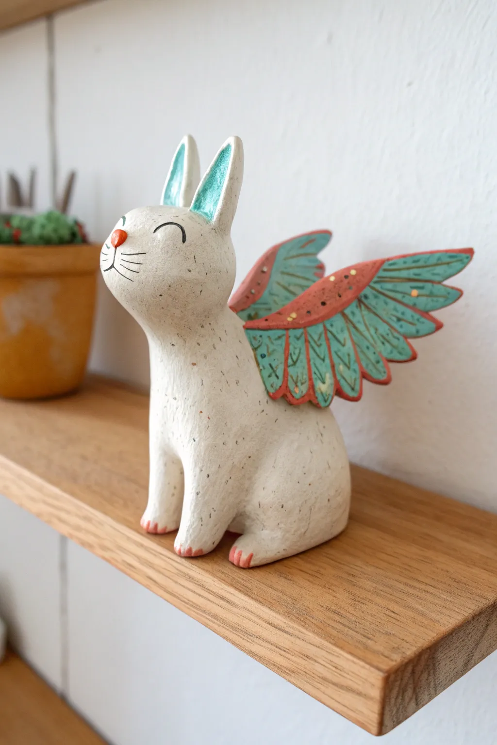 A playful winged cat hybrid in bright glaze accents, styled simply for modern boho shelves.