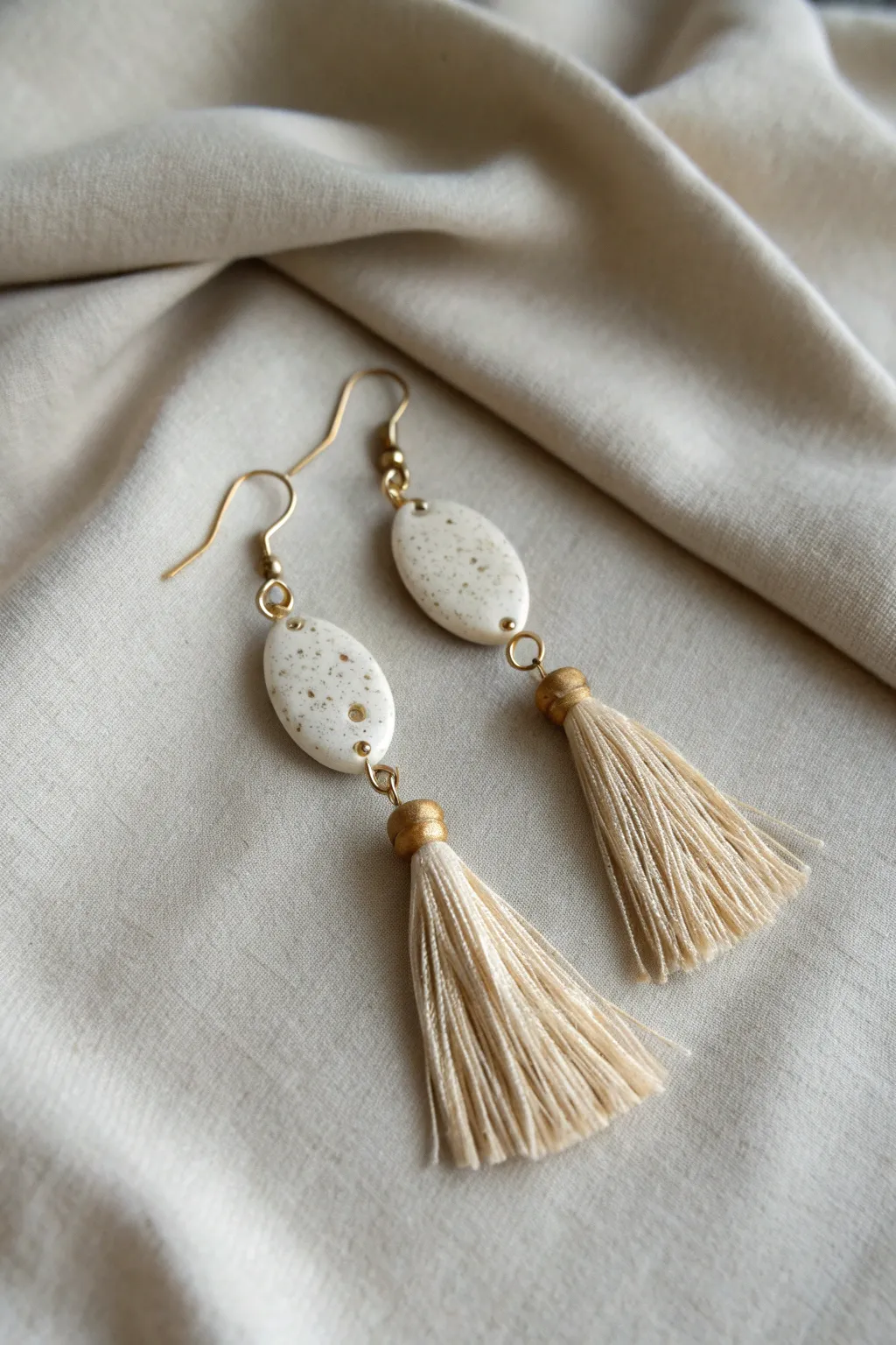 Minimal mixed-media earrings: matte ceramic drops paired with soft cotton tassels