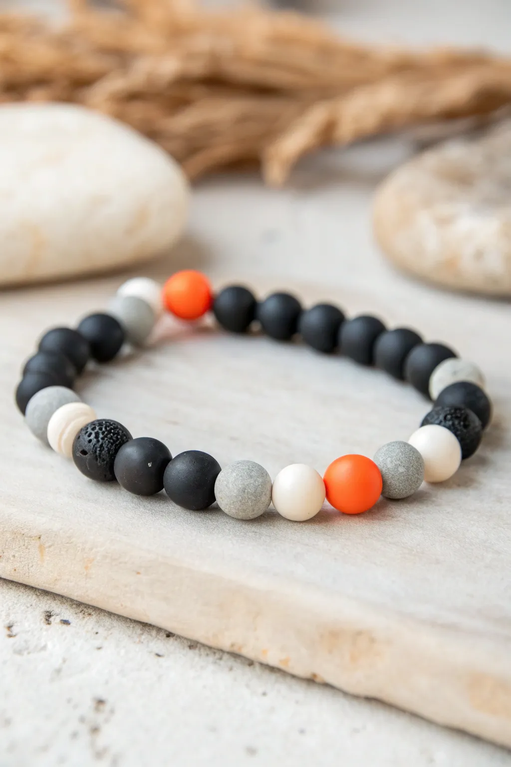 Moody monochrome clay bracelet with a neon orange pop bead for a chic, modern color combo.