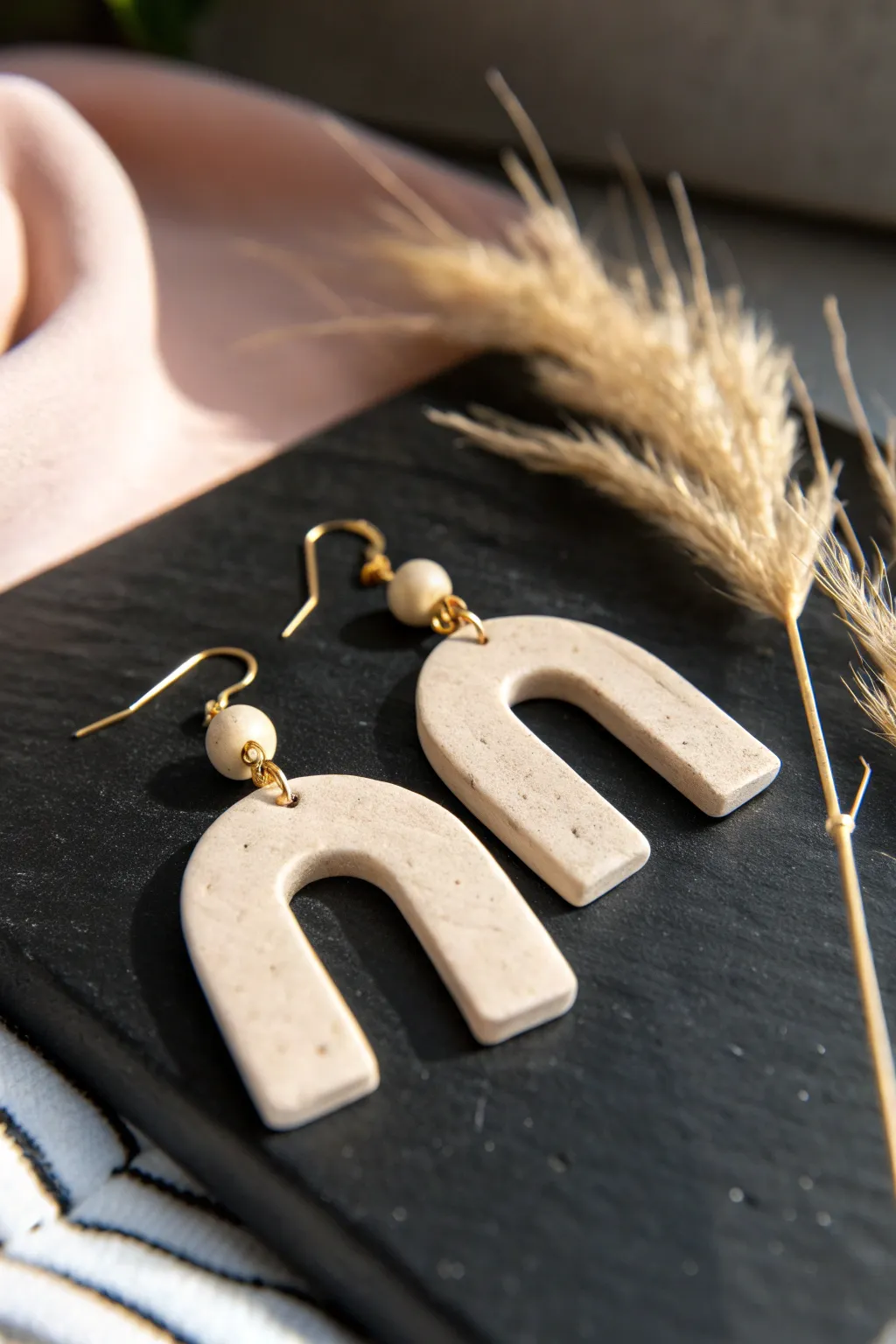 Minimal clay earring with a soft gold rim, crisp contrast on matte black background.