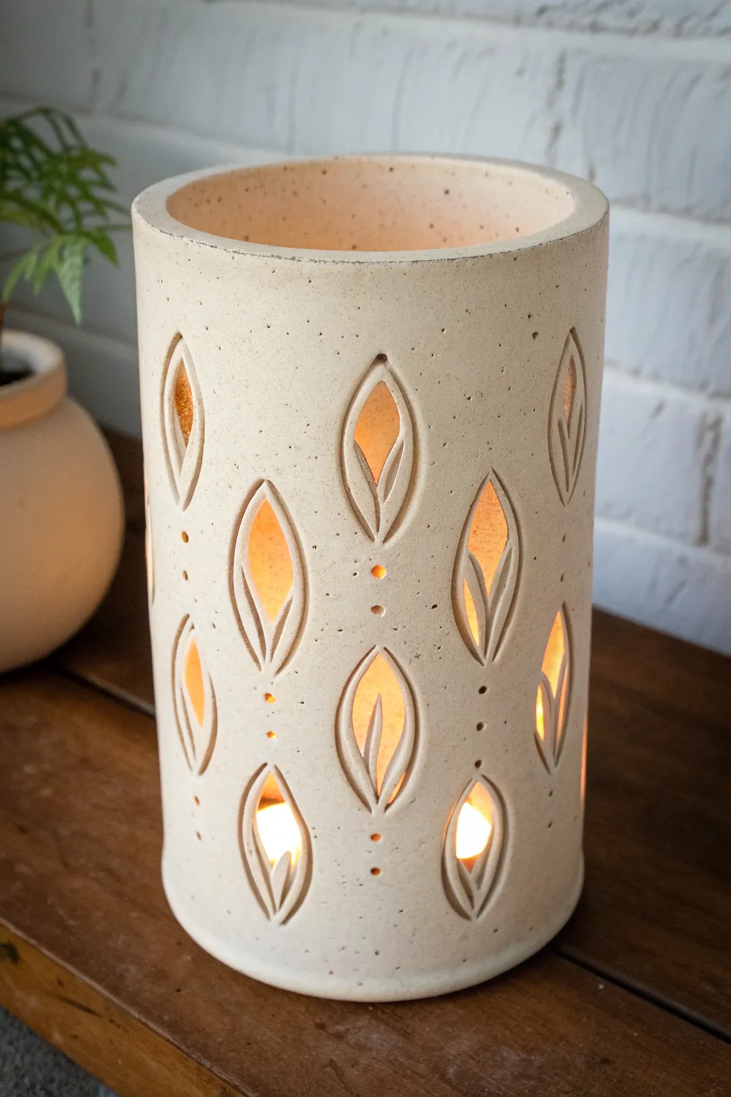 Sgraffito lines catch the light as warm cutouts glow for an elegant clay luminary contrast.