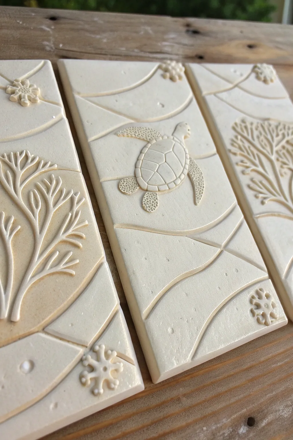 Serene clay triptych relief tiles with waves, turtle, and coral flowing across three panels.