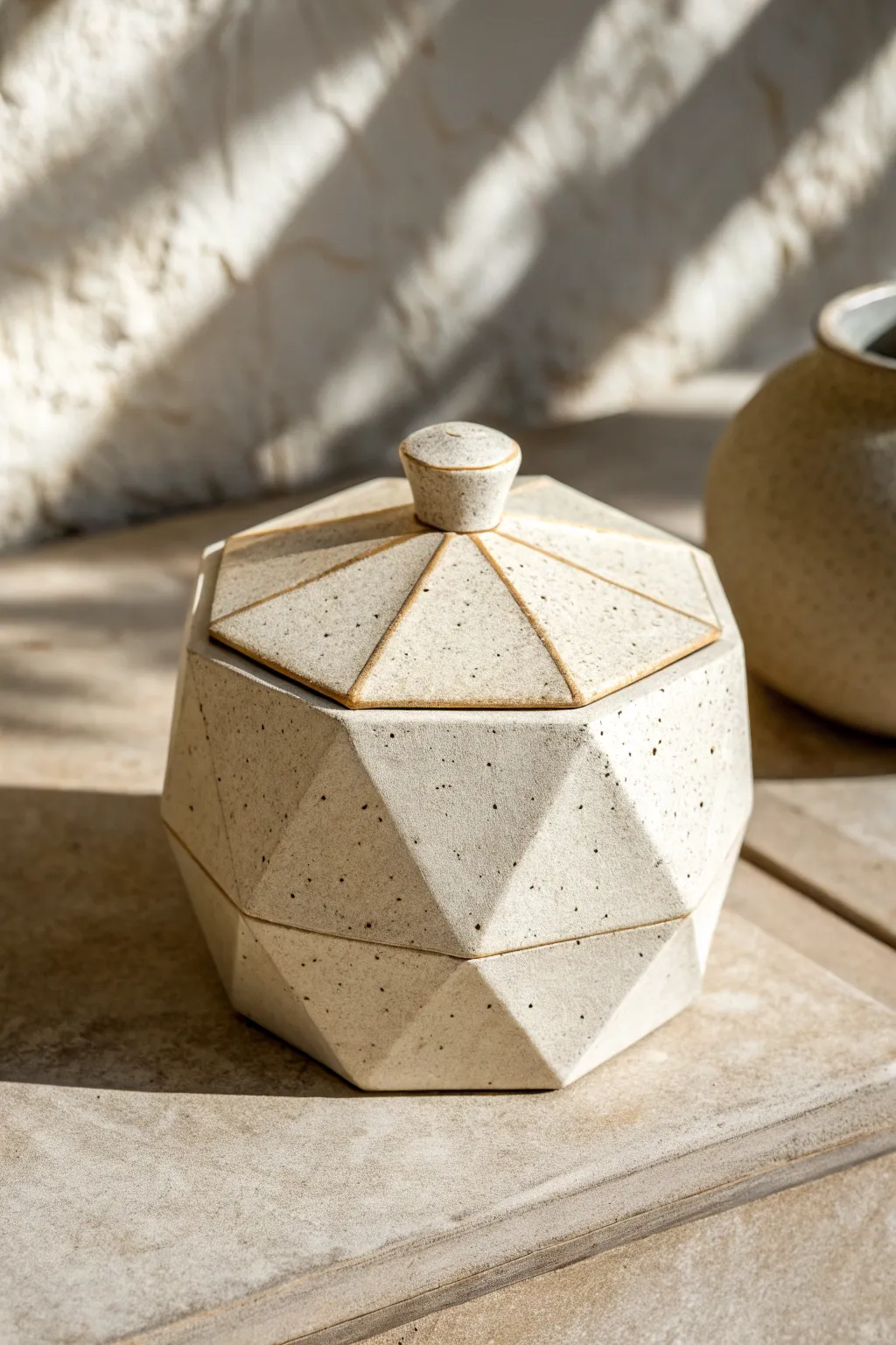 Facet-wall slab container with a matching lid, crisp angles and striking sculpted shadows.