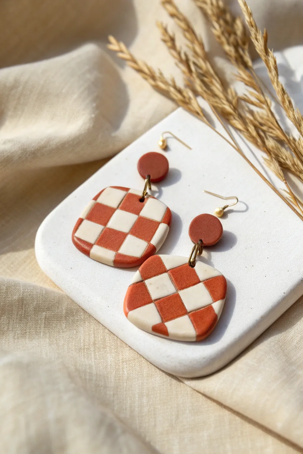 Bold checkerboard polymer clay earrings in terracotta and ivory, simple handmade vibe.