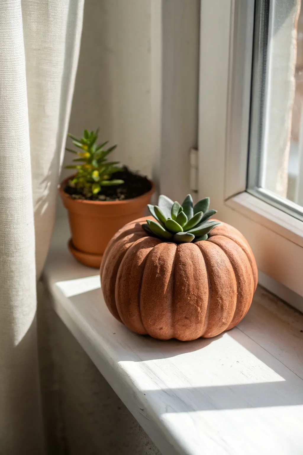 Pumpkin clay planter with a tiny succulent, perfect for cozy fall windowsill styling.