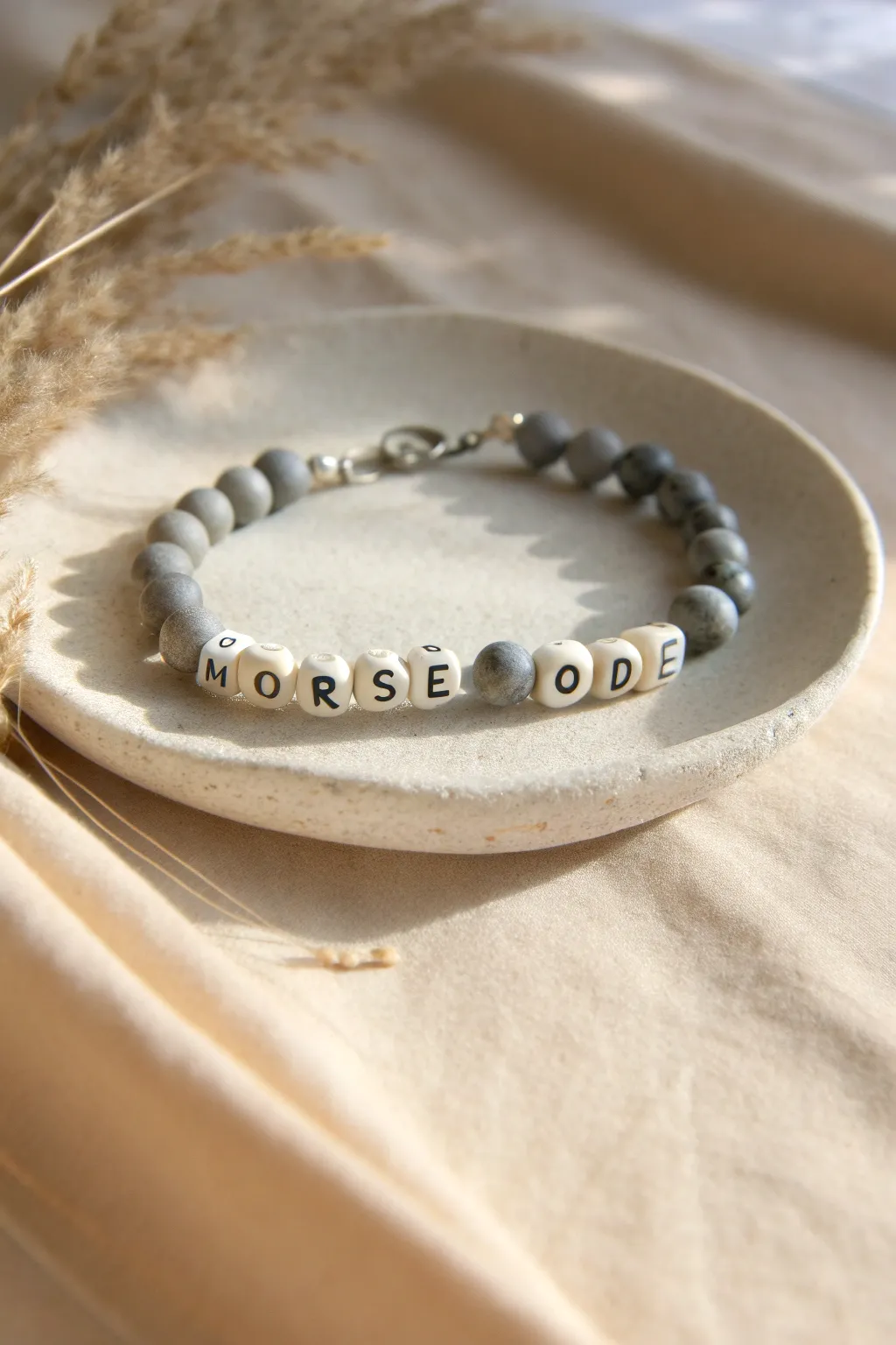 Grey clay beads with a subtle Morse code pattern, minimalist and boho in soft natural light.