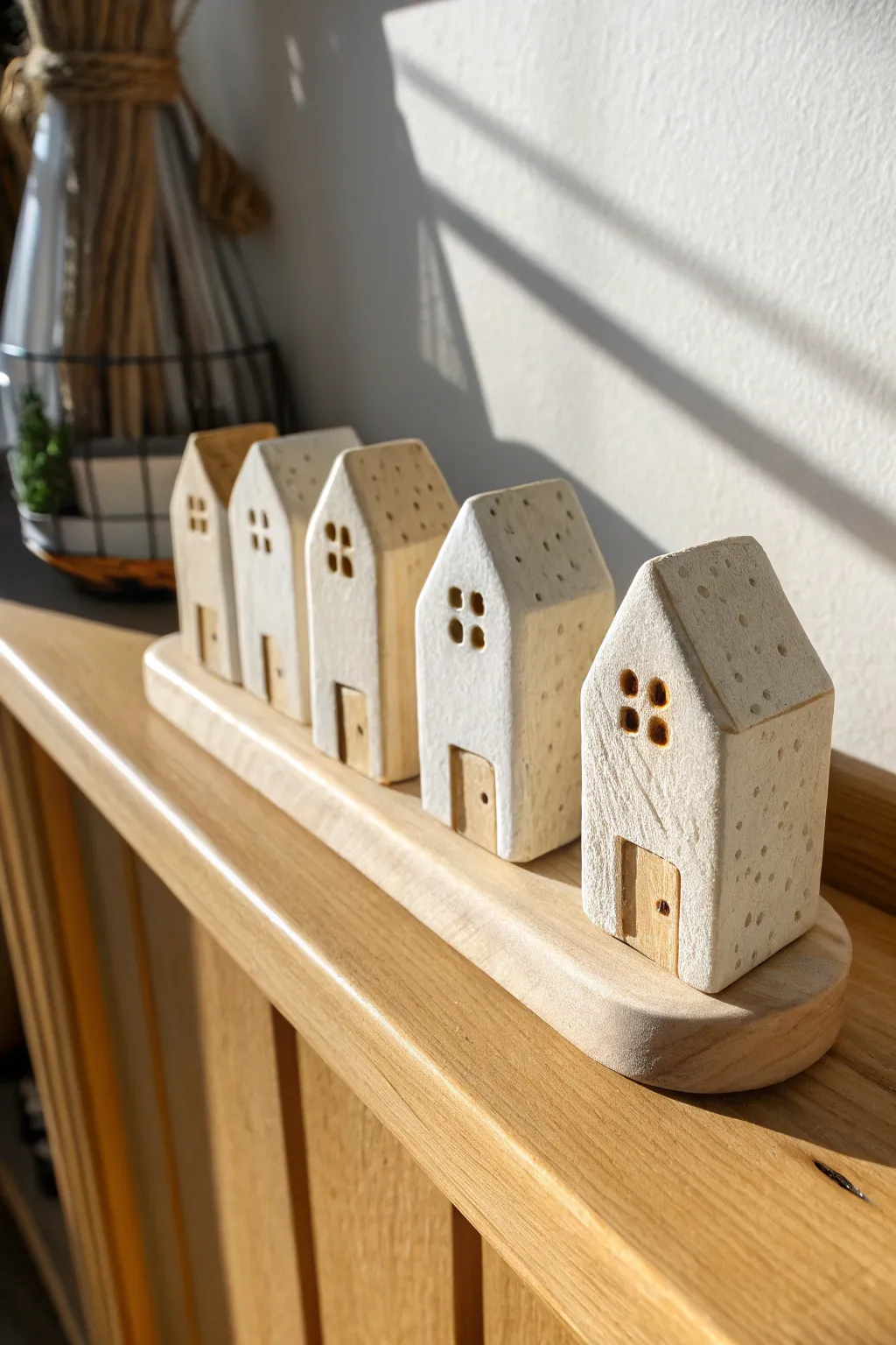 Micro clay cottage village on a shelf, minimalist Nordic tones with cozy boho warmth