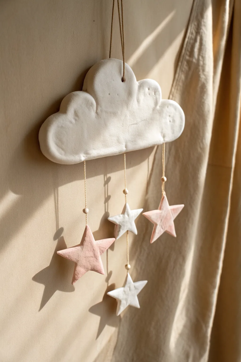 Dreamy cloud clay hanging with dangling stars in soft pastels, minimal and calming decor.