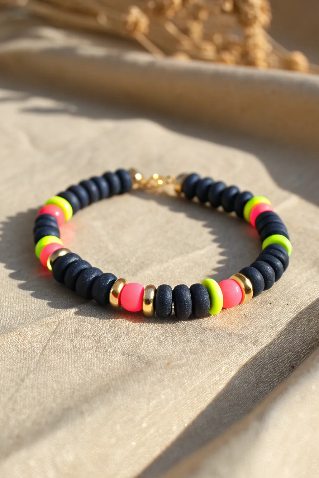 Neon pops on a dark clay disc bracelet for an effortless summer night statement