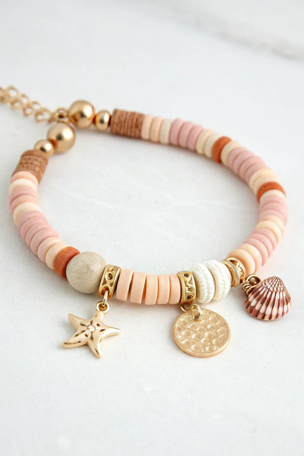 Minimal clay heishi bracelet with charm cluster and gold spacers, perfect statement piece.