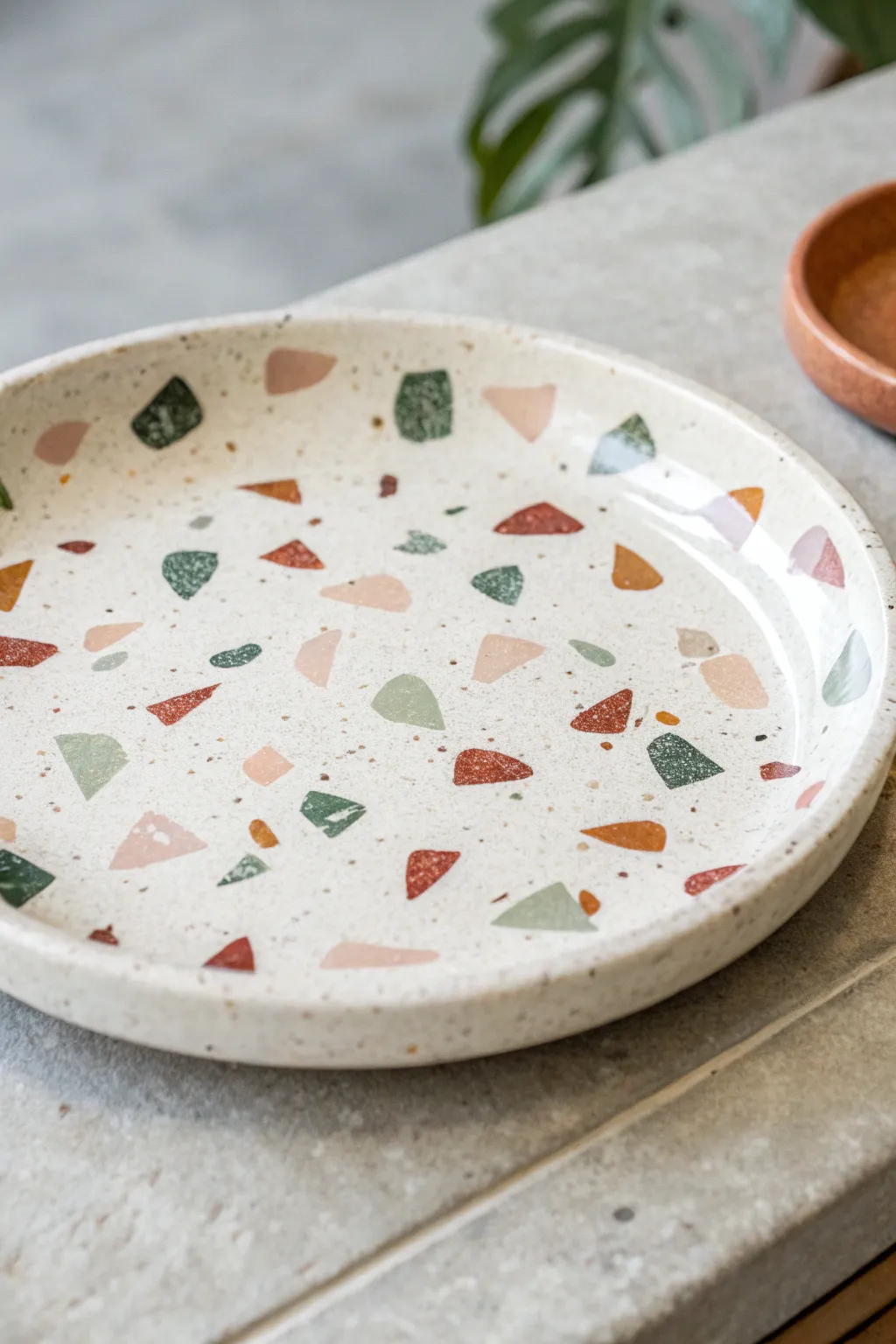 Terrazzo-inspired clay plate with glossy confetti inlay, minimalist yet playful for modern tables
